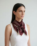 Vinröd sidensjal i siden med blommönster knuten runt halsen i klassisk stil