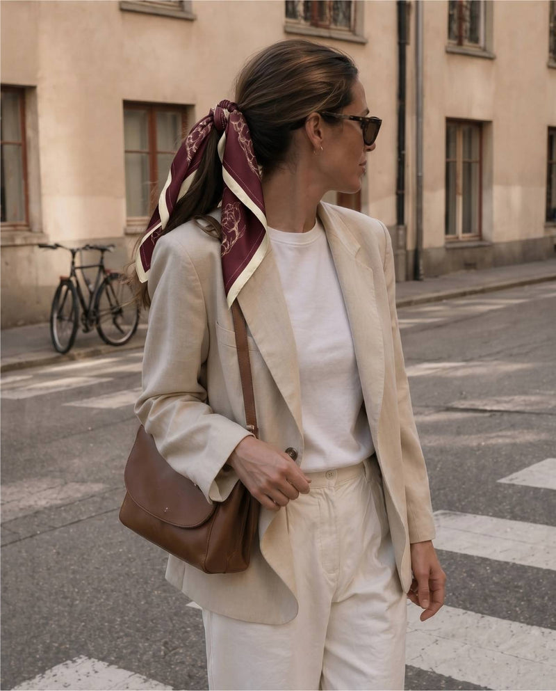 Kvinna på väg till kontoret klädd i beige linnekostym, vit t-shirt och vinröd, blommig sidensjal.